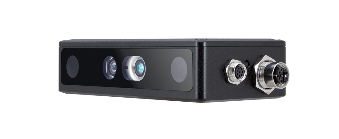 A black rectangular device with two lenses and additional sensors on the front panel. The side features industrial-grade connectors, including circular metallic ports. The background is solid black, showcasing the device's robust and functional design.