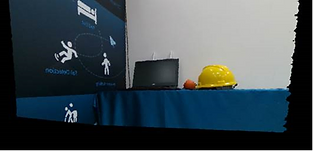 LIPSedge™ AE430 Industrial 3D Camera with Edge Processing Capability 7 A desk setup featuring a laptop, a yellow safety helmet, and an orange ball, placed against a blue backdrop with industrial-themed graphics.